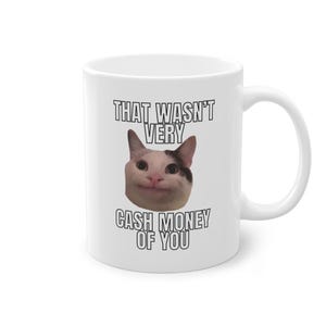 Könnte beinhalten: Weiße Keramiktasse mit einem Schwarzweißbild einer Katze mit dem Text "That wasn't very cash money of you".