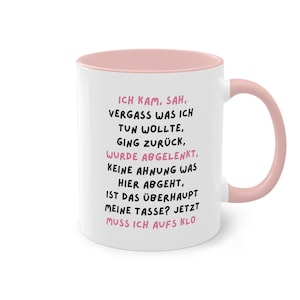 Könnte beinhalten: Weißer Keramikbecher mit rosa Innenraum und Henkel. Der Becher hat schwarzen und rosa Text auf Deutsch. Der Text lautet: "ICH KAM, SAH, VERGASS WAS ICH TUN WOLLTE..." Ein humorvoller Kaffeebecher.