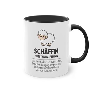 Könnte beinhalten: Weißer Keramikbecher mit schwarzem Innenraum und Henkel. Der Becher zeigt eine Cartoon-Schaf-Illustration und deutschen Text, darunter "SCHÄFFIN" und "SUBSTANTIV, FEMININ". Zusätzlicher Text beschreibt das Thema des Bechers.
