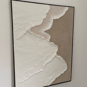 May include: Abstract painting with textured white and beige paint in a black frame.