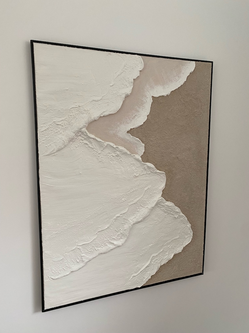 May include: Abstract painting with textured white and beige paint in a black frame.