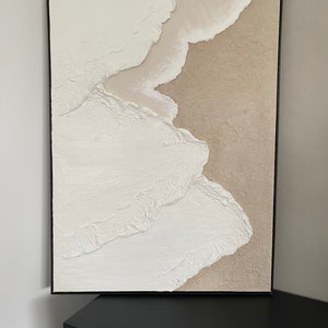 May include: Abstract painting with textured white and beige paint in a black frame.