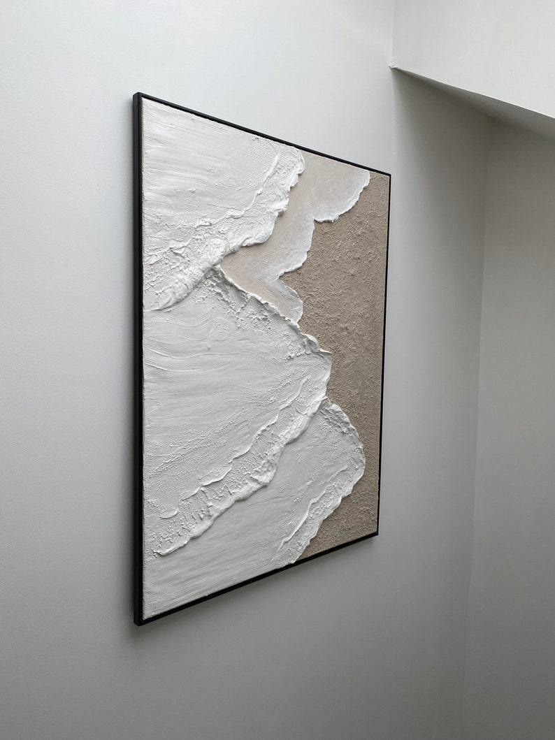 May include: Abstract painting with white and beige textured paint on canvas, framed in black.