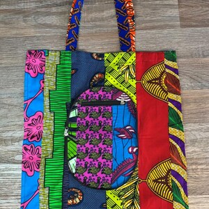 Peut inclure: Sac fourre-tout coloré avec un motif patchwork. Le sac présente une variété de motifs et de couleurs vives, notamment le bleu, le vert, le rouge et le violet. Il possède une poche zippée circulaire et des anses assorties.