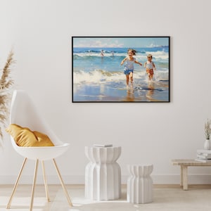 May include: A painting of two children running on a beach with waves crashing behind them. The painting is framed in black and hangs on a white wall.
