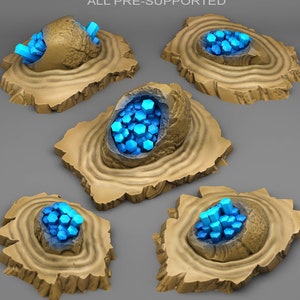 Puede incluir: Cinco bases de resina impresas en 3D pre-soportadas con una superficie texturizada y una depresión circular en el centro. Cada depresión contiene un grupo de cristales azul brillante.