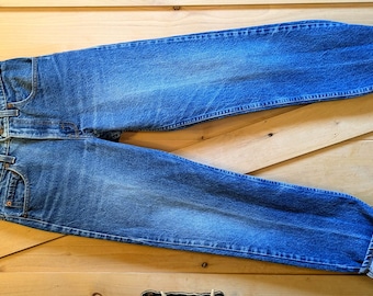 Puede incluir: Un par de pantalones vaqueros azules de mezclilla con piernas remangadas. Los vaqueros tienen un estilo clásico de pierna recta y están hechos de una tela suave y cómoda.