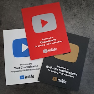 May include: Three YouTube Play Button awards in red, white, and black. The red award is for 10,000 subscribers, the white for 100,000, and the black for 7,500. Each features the YouTube logo and text.