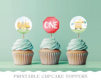 Op de afbeelding: Printbare cupcake-toppers met een gele schoolbus, een rood stopbord met het woord "EEN" en een blauw-gele schoolbus met ballonnen. De toppers zijn op cupcakes met lichtblauwe frosting.