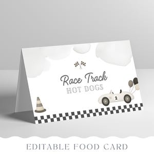 May include: A white, folded food card with a race car theme. The card features the text "Race Track HOT DOGS", a cartoon race car, checkered flags, a traffic cone, and balloons. The bottom of the card reads "EDITABLE FOOD CARD".