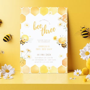 May include: A yellow and white birthday invitation with a honeycomb pattern and two cartoon bees. The text reads "So sweet to bee three. Please join us to celebrate Amelia's 3rd. Bee-Day. 14|06|2024 Saturday at 3:00 PM 123 Anywhere St. Any City RSVP to 612-456-7890"