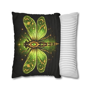May include: A rectangular throw pillow featuring a black front panel with a large, detailed green and gold dragonfly illustration adorned with stars, moons, and floral motifs. The side panel displays a white and grey horizontal striped pattern.