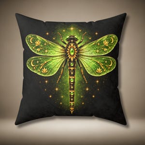 May include: A square throw pillow featuring a black background with a central illustration of a green dragonfly. The dragonfly has translucent wings with gold floral and crescent moon accents, a dark body with green circular gems, and a glowing green aura surrounded by small golden stars.
