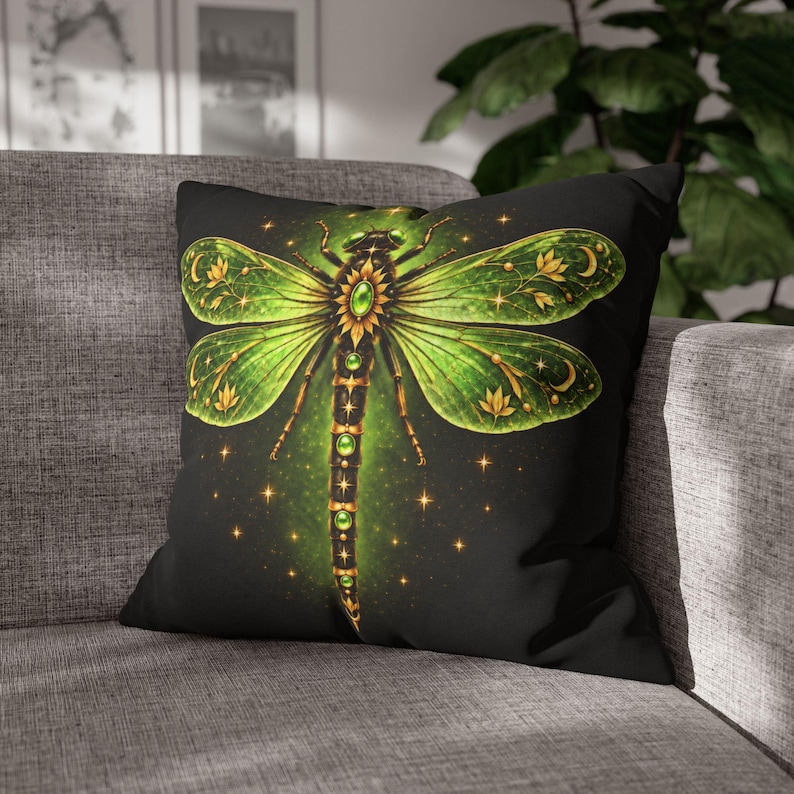 May include: A square throw pillow featuring a black background with a large, detailed dragonfly illustration. The dragonfly has vibrant green, translucent wings adorned with gold floral and crescent moon patterns, and a body set with green gems.
