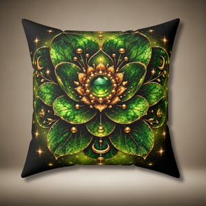 May include: A square throw pillow featuring a symmetrical, layered floral design in shades of deep green and gold. The centre displays a glowing green gemstone surrounded by golden petals, with radiating leaf-like patterns and small crescent moon accents.