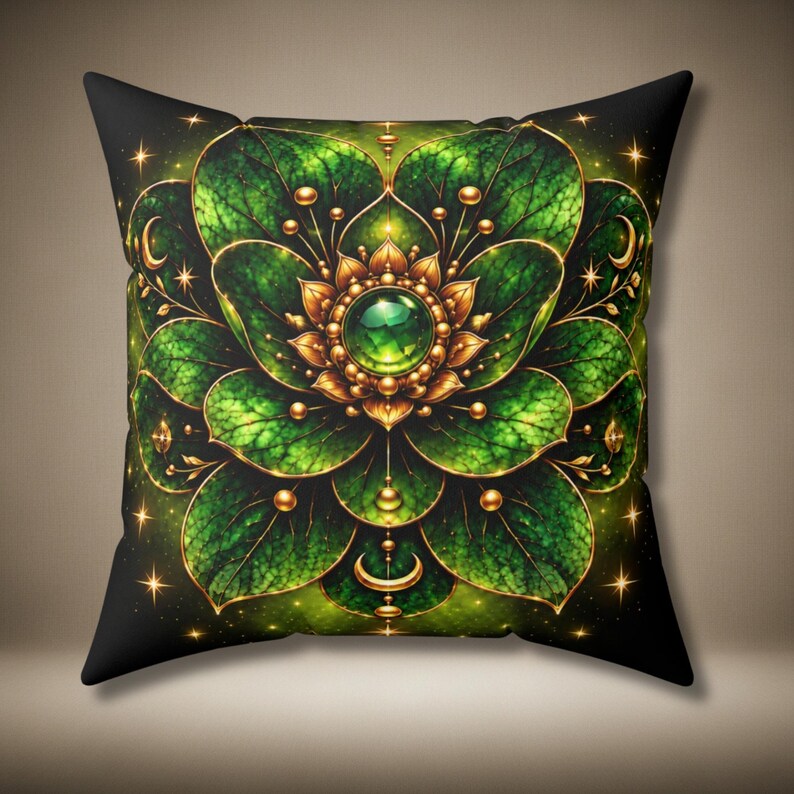 May include: A square throw pillow featuring a symmetrical, layered floral design in shades of deep green and gold. The centre displays a glowing green gemstone surrounded by golden petals, with radiating leaf-like patterns and small crescent moon accents.