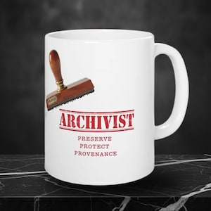 May include: White ceramic mug with the word "ARCHIVIST" in red, along with "PRESERVE PROTECT PROVENANCE." A wooden stamp with a brass fitting is next to the mug. The mug has a large handle.