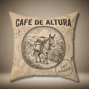 May include: Square cushion with a vintage coffee theme. The cushion features a circular illustration of a donkey carrying bags of coffee beans, with the text "CAFÉ DE ALTURA" and "CAFÉ ORGANICO". The design is in shades of brown and beige.