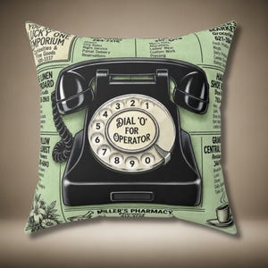 May include: A square throw pillow with a light green background featuring a black rotary telephone graphic in the centre. The dial includes the text DIAL O FOR OPERATOR. The surrounding print mimics a vintage newspaper with various business advertisements.