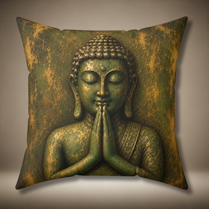 May include: A square throw pillow featuring a printed image of a Buddha figure with closed eyes and hands pressed together in a prayer position. The design displays a distressed, weathered texture in shades of dark green and metallic gold.