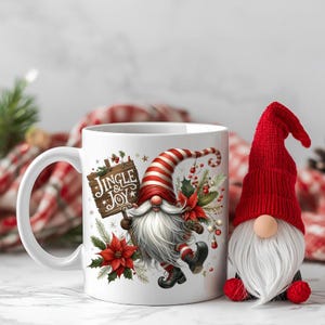 May include: White ceramic mug with a Christmas gnome design holding a sign that reads "Jingle & Joy." The gnome has a red and white striped hat, a long white beard, and is surrounded by poinsettias. A small gnome figure with a red hat is next to the mug.