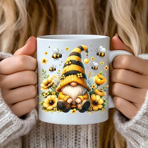 May include: White ceramic mug with a yellow and black bee gnome design. The gnome is wearing a yellow and black striped hat and holding a flower. There are bees and flowers surrounding the gnome.