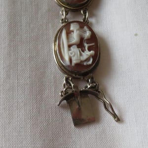 May include: A vintage cameo bracelet featuring oval brown and white carved stone pendants. The bracelet has a silver-toned metal chain and clasp. The cameos depict classical figures.