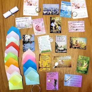 May include: A collection of colourful envelopes, fairy-themed cards, and charms with inspirational messages. The cards feature fairies, flowers, and whimsical designs. The messages include "You are beautiful inside and out", "Never underestimate anything other than your amazing self", and "A kind friend is the night kind of friend".