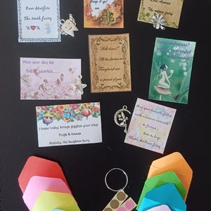 May include: A collection of colorful envelopes with fairy-themed messages and charms. The messages include encouraging words, well wishes, and congratulations. The charms are silver and include a tooth, a four-leaf clover, a star, a crescent moon, and a key.