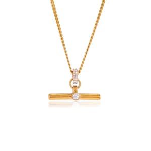 May include: Gold-toned necklace featuring a T-bar pendant with a single, clear gemstone. The pendant is suspended from a delicate chain. The necklace also has a small, circular accent with embedded gemstones.