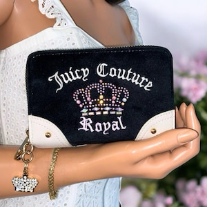 May include: Black wallet with the text "Juicy Couture Royal" and a jeweled crown design. The wallet has a black exterior with white and gold accents. A gold chain with a jeweled crown charm is attached.
