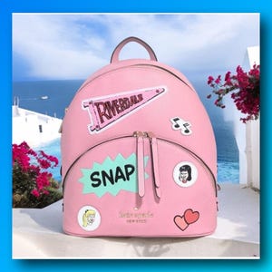 May include: A light pink leather backpack featuring a top handle, dual zipper pulls, and various patches including a pink Riverdale pennant, a mint green burst with the text SNAP, musical notes, a cartoon face, and two pink hearts.
