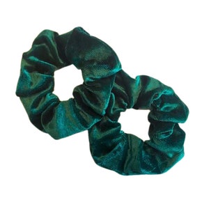 May include: Two green velvet scrunchies. The scrunchies are made of a soft, plush fabric and are perfect for holding hair in place.