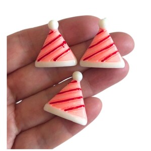 May include: Three pink and white party hats with red stripes. The hats are made of plastic and are about 1 inch tall.