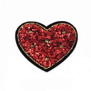 May include: Red heart-shaped patch with gold glitter and black trim.