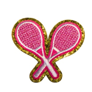 May include: A decorative patch featuring two crossed tennis rackets. The rackets are pink with white and silver accents, set against a gold glitter background. This patch is ideal for adding a sporty touch to clothing or accessories.