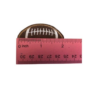 May include: A brown and white embroidered football patch measuring approximately 1 inch in diameter.