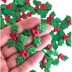 May include: A large quantity of green and red glitter holly leaves. The leaves are made of a shiny, metallic material and have a three-dimensional shape.