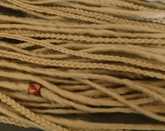 Könnte beinhalten: Nahaufnahme eines Bündels hellbrauner synthetischer Dreadlocks mit einem roten Perlenakzent. Die Dreadlocks bestehen aus einem weichen, strukturierten Material.