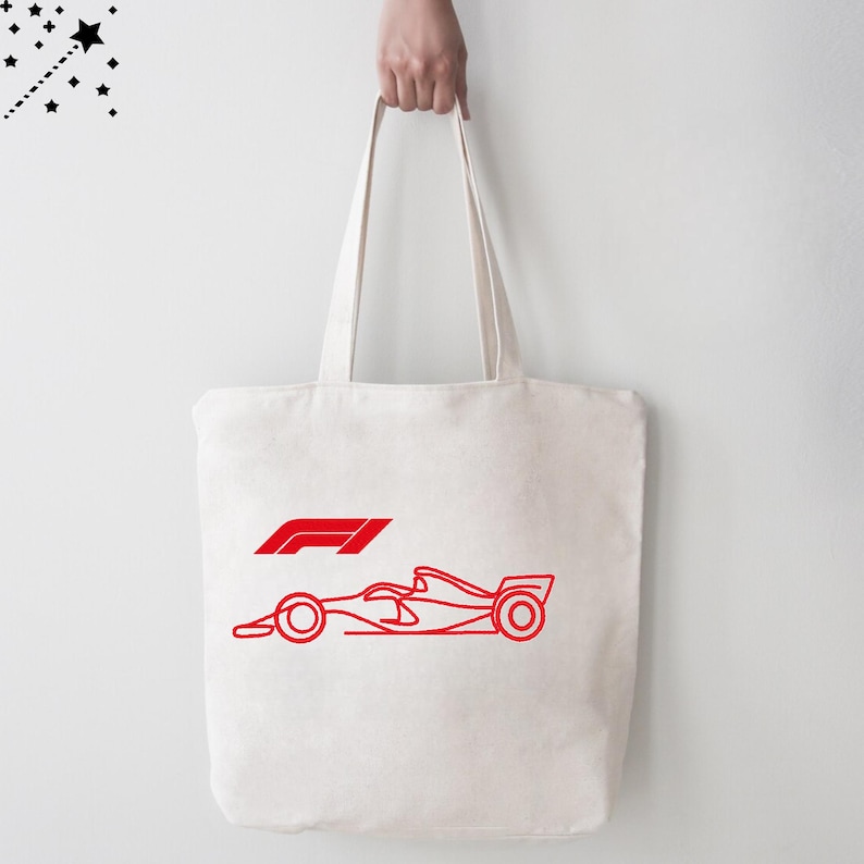 Op de afbeelding: Cr&egrave;mekleurige draagtas met een rode omtrek van een Formule 1-raceauto en het F1-logo. De tas heeft twee lange handvatten en wordt door een persoon omhooggehouden.