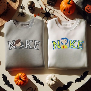 May include: Two gray sweatshirts with the word "NOKE" printed on them. One sweatshirt features a cartoon boy, the other features a cartoon girl.