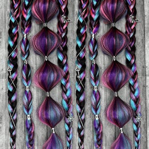 Puede incluir: Dos conjuntos de extensiones de cabello trenzado de colores. Las trenzas presentan una mezcla de mechones negros, turquesa, rosa y morado. Cada trenza está adornada con acentos decorativos bulbosos en tonos morados y rosas, y abalorios plateados.