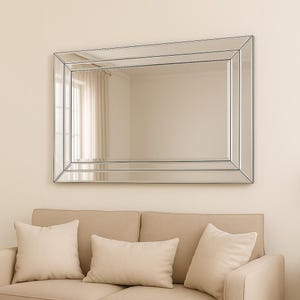 May include: A rectangular wall mirror featuring a bevelled glass frame with multiple layered panels. The mirror has a clean, reflective surface with angled edges that create a stepped, dimensional appearance around the central glass pane.