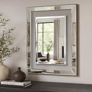 May include: A rectangular wall mirror featuring a double-layered frame design with bevelled glass edges. The mirror has a central reflective panel surrounded by a secondary mirrored border, creating a layered, reflective appearance on the wall.
