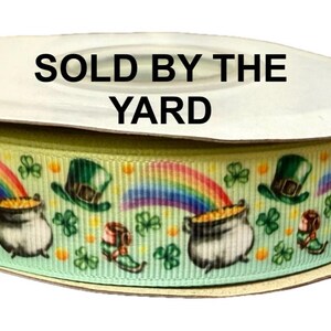 Può includere: Nastro verde, giallo e blu con un motivo ripetitivo di folletti, pentole d'oro e arcobaleni. Il testo "SOLD BY THE YARD" è stampato sul rotolo.