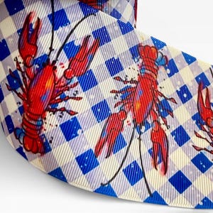Könnte beinhalten: Gerollter Stoff mit blau-weißem Karomuster, verziert mit roten Hummer-Illustrationen. Das Design umfasst schwarze Linien und blaue Aquarellakzente, wodurch eine einzigartige und ansprechende Ästhetik entsteht.
