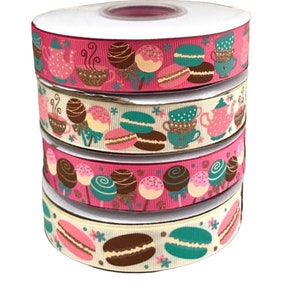 Op de afbeelding: Vier spoelen roze en crèmekleurig lint met een herhalend patroon van cupcakes, macarons, theekopjes en theepotten.