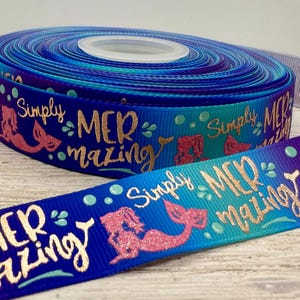 Könnte beinhalten: Rolle aus blauem und türkisem Band mit dem goldenen Schriftzug „Simply MERmazing“. Das Band zeigt rosa Glitzer-Meerjungfrauen-Illustrationen und türkisfarbene Blasen. Ideal zum Basteln und Geschenkverpacken.