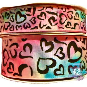 Può includere: Due rotoli di nastro tie-dye rosa e blu con disegni di cuori neri. Il nastro è largo 3,8 cm.