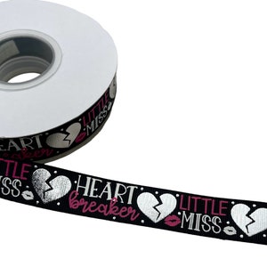 Könnte beinhalten: Schwarzes Band mit einem sich wiederholenden Muster aus silbernen gebrochenen Herzen, rosa Lippen und dem Text "Heartbreaker Little Miss" in weißer und rosa Schrift.